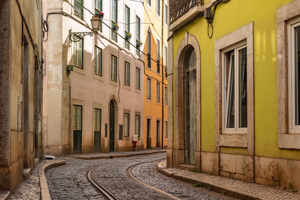 Curving tram tracks between colorful facades in Lisbon’s Alfama.
